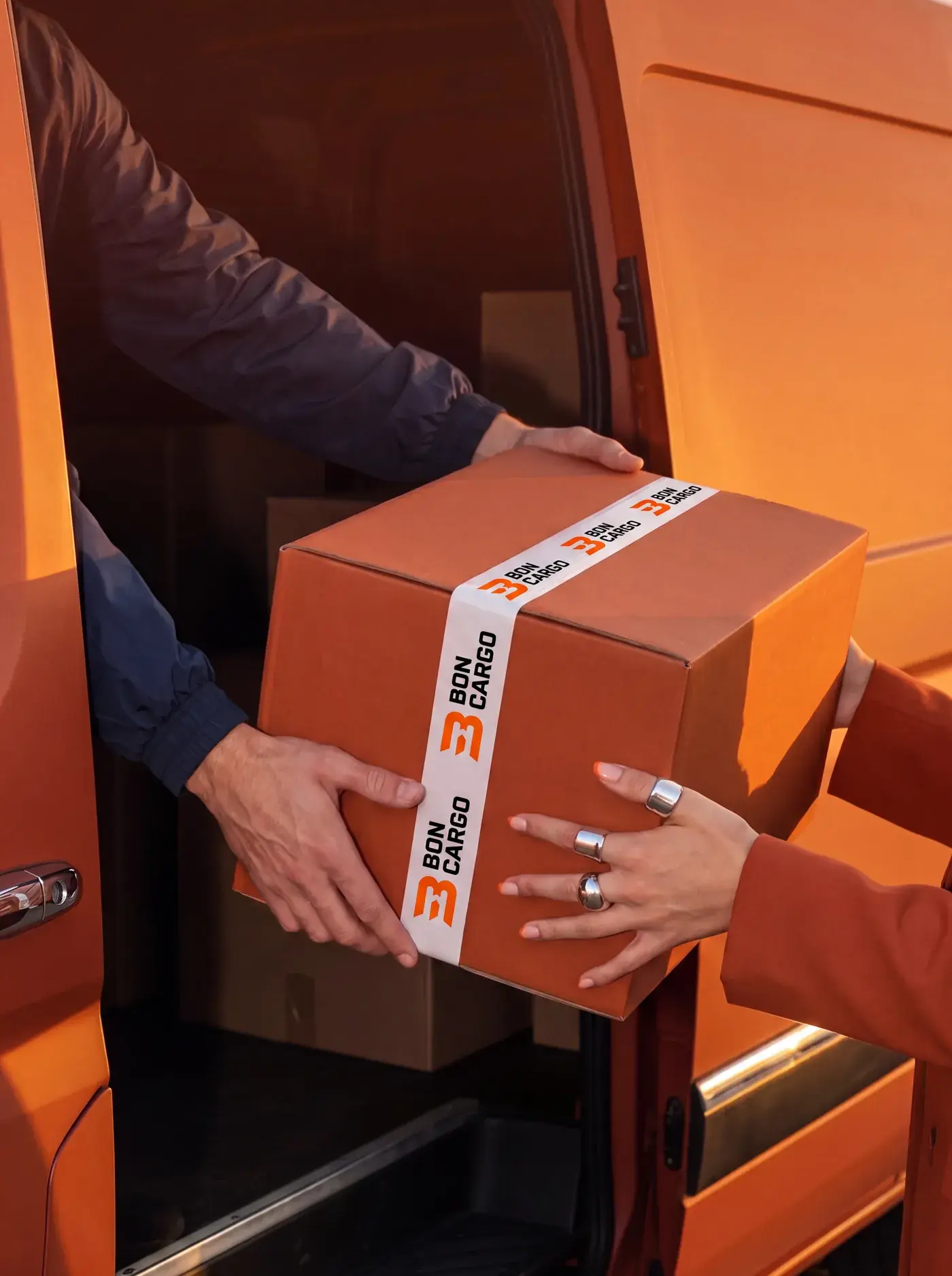 A BonCargo parcel sealed with branded tape being handed over at a delivery van